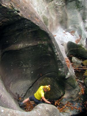 John makes his way carefully down the blockage fish rock to get back to the bottom of the slot canyon 
